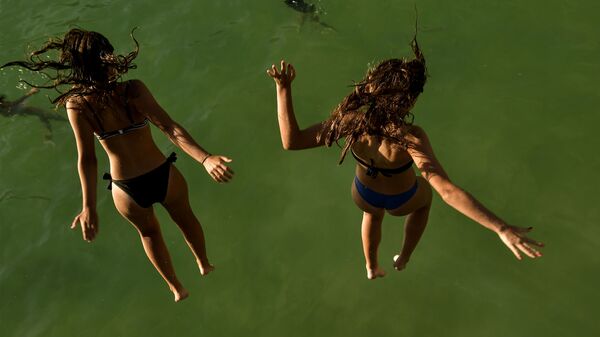 Девушки прыгают в море на пляже la concha, Испания