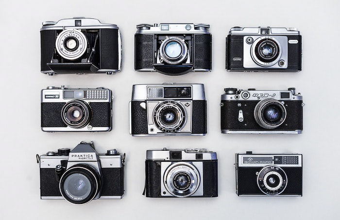 A flat lay of nine old film cameras on a white background - professional photo shoot