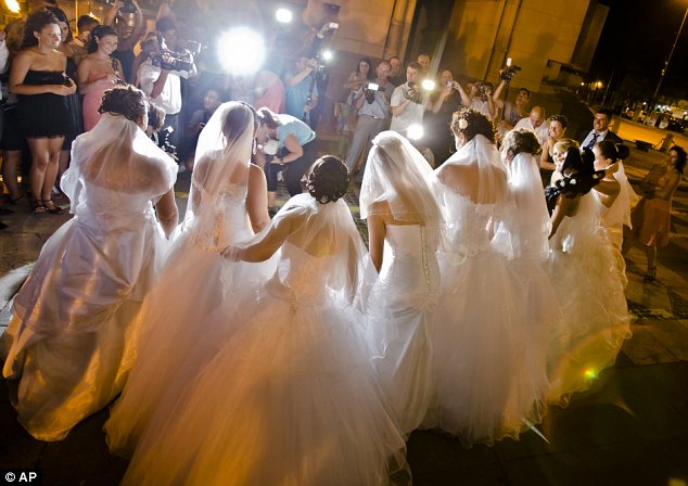 Romanian brides pose for pictures under the Triumph Arch in Bucharest, Romania