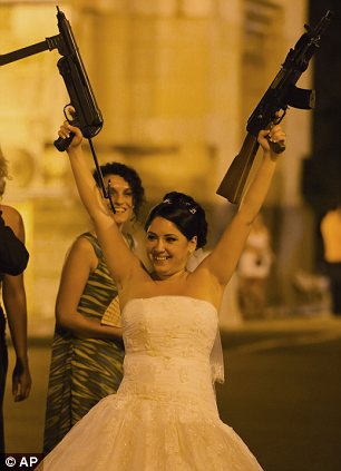 a Romanian bride holds toy weapons in the air at the Triumph Arch in Bucharest, Romania