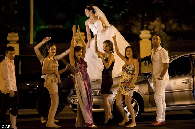 a Romanian bride dances on a car at the Triumph Arch in Bucharest, Romania