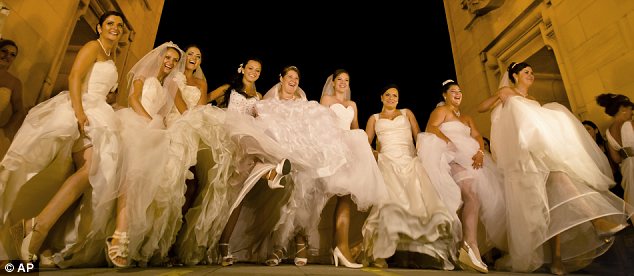 Romanian brides pose for pictures under the Triumph Arch in Bucharest, Romania